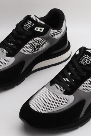 A pair of black, white, and grey athletic sneakers with prominent "LOUIS VUITTON PARIS" branding on the tongue, white mesh panels, black suede overlays, and grey accents on the sides, displayed from a top-down angle against a plain white background.