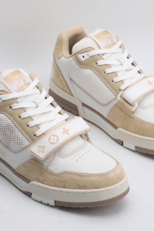 "A pair of DesertBloom Beige and White Urban Sneakers, viewed from an angle, showcasing their low-top design, white laces, beige suede and textile accents, white leather panels, and distinctive strap across the vamp."