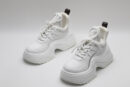 A pair of white Louis Vuitton LV Archlight chunky sneakers, showcasing their distinctive wave-shaped outsole, leather and technical fabric upper, and subtle monogram details.