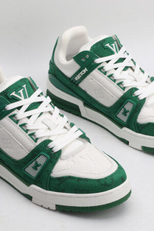 A pair of Louis Vuitton LV Trainer Low-Top Sneakers in green and white monogram canvas, viewed from an elevated angle, showcasing both shoes with green monogram canvas panels and white leather details.