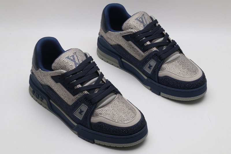 A pair of navy blue and silver Louis Vuitton LV Trainer sneakers, showcasing their bicolor design, textured panels, and robust outsole with "VUITTON" branding.