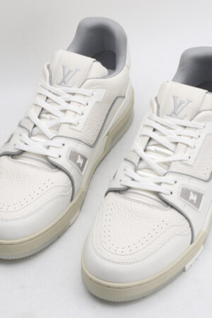 A pair of white Louis Vuitton LV Trainer sneakers with light grey accents and a beige outsole