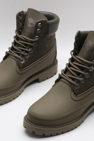A pair of olive green Timberland x Louis Vuitton collaborative waterproof boots, featuring the Timberland tree logo and subtle Louis Vuitton monogram debossing on the upper.