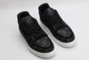 A pair of Louis Vuitton LV Trainer sneakers in black and grey monogram, featuring a white midsole and translucent outsole