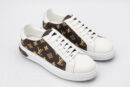 A pair of low-top sneakers with a brown and gold monogram pattern on the sides and white leather on the toe, tongue, and heel. The shoes have white laces and a thick white rubber sole, and are shown from a slightly elevated side angle on a clean white background.