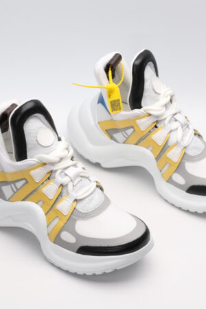 A pair of white, light blue, and black multi-panel chunky sneakers with a thick white sole, red and yellow accents, and a distinctive brown logo tag. The sneakers are photographed on a clean white background from a slightly elevated side angle.