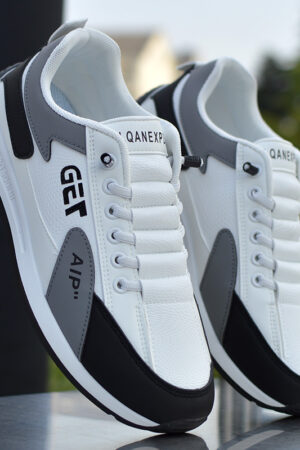 A pair of white unisex sneakers with black and gray accents, featuring a "TOSHA" logo on the side and a textured sole.
