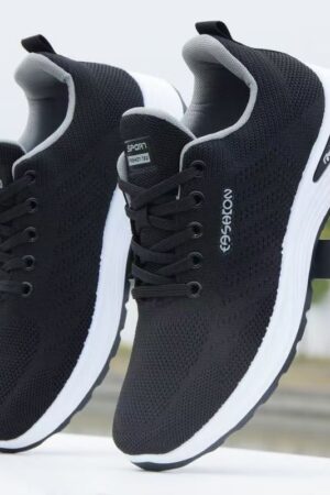 A black and white casual sneaker with a knit upper, a thick layered sole, and GUCCI branding on the side and tongue.