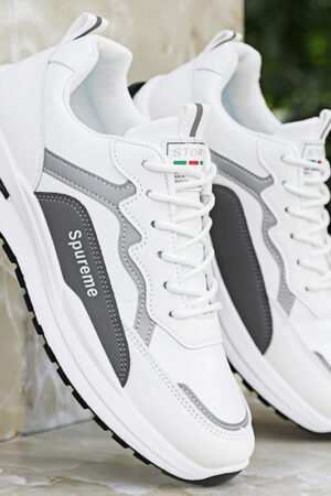 A pair of unisex running shoes with a multi-paneled design in black, white, and gray, featuring letter details on the side.