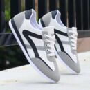 A pair of luxury unisex sneakers in a white, black, and gold color scheme with a bold, urban-inspired design.