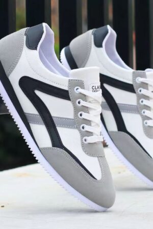 A pair of luxury unisex sneakers in a white, black, and gold color scheme with a bold, urban-inspired design.