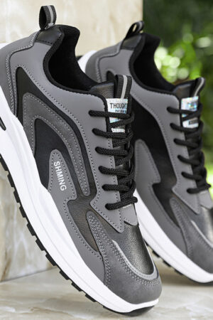 A pair of gray, black, and white unisex casual sneakers with a layered design and a thick sole.