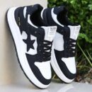 A pair of chunky unisex walking sneakers in black and white with a star graphic on the side and a layered sole.