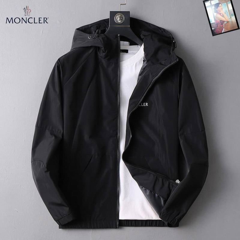 Black nylon Moncler hooded jacket with white logo tape repeating vertically along the main zipper and surrounding the hood's edge.