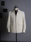 A cream white fine-wale corduroy flight jacket with two flap pockets and a silver zipper, styled on a mannequin with a grey shirt.