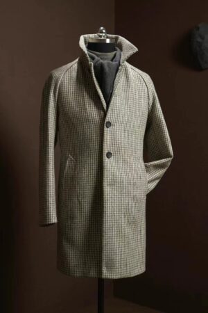 A high-quality men's overcoat featuring a tan and brown houndstooth pattern, raglan sleeves, and a standing collar, displayed on a mannequin.