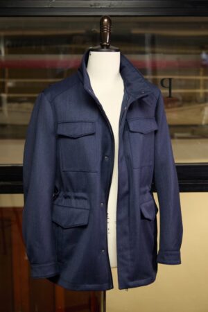 Navy blue Burberry style technical wool field jacket with a funnel neck, zip-up front, and elasticated waist on a white mannequin.