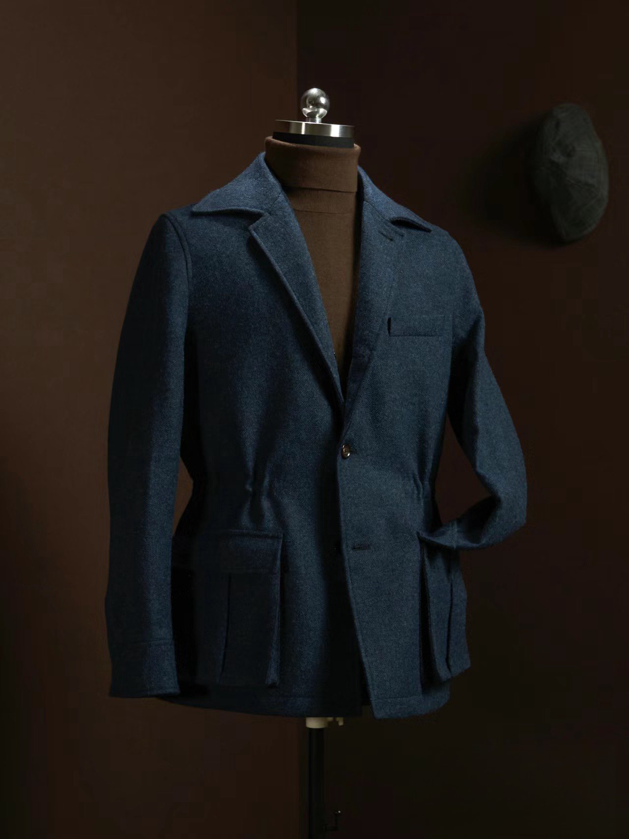 Burberry style navy blue wool utility blazer on a mannequin, featuring a notched lapel, cinched waist, and large cargo pockets.