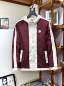 Front view of a burgundy and white hooded windbreaker jacket with sleeve stripes and a chest logo, hanging in a luxury retail setting.