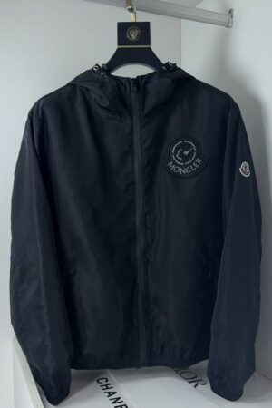 Black Moncler x Fragment collaborative windbreaker with a large circular logo on the chest, adjustable hood, and signature felt logo on the sleeve.