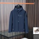 Navy blue Moncler soft-shell jacket with "MONCLER" printed on the chest, tricolor zip details, and a black logo patch on the left sleeve