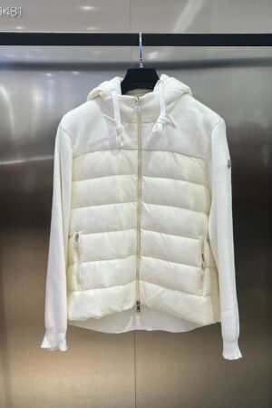 A white hooded hybrid jacket displayed on a hanger, featuring a horizontally quilted puffer panel on the front torso and white ribbed knit material on the sleeves and back. A small logo patch is visible on the left arm