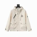 A cream-colored premium utility field jacket with two large front cargo pockets, a vertical chest zipper, and a signature logo patch on the chest.