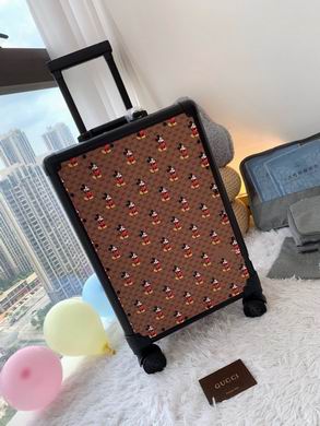 A Gucci x Disney rolling suitcase featuring brown GG Supreme canvas with Mickey Mouse prints and a black telescopic handle in a modern room.