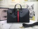 A Gucci Savoy duffle bag in black and grey GG Supreme canvas with a blue and red center stripe and gold GG logo on a marble table.