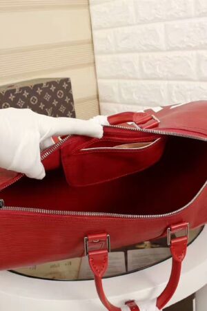 A high-quality Louis Vuitton x Supreme inspired Keepall Bandoulière travel bag in red textured Epi leather with white branding and a wide zippered opening