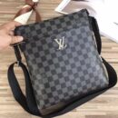 A high-quality Louis Vuitton inspired Mick messenger bag in black and charcoal Damier Graphite canvas with a silver logo and black textile strap.
