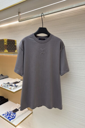 premium Louis Vuitton short-sleeved T-shirt in anthracite grey hanging on a black hanger, featuring an embossed LV monogram on the center chest.