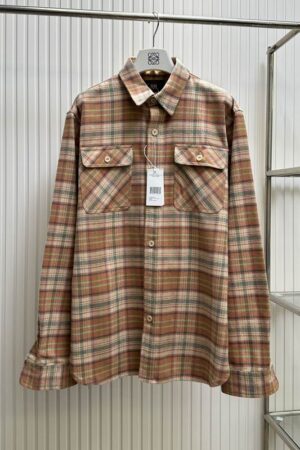 A premium men's long-sleeve western shirt in an orange, blue, and cream plaid pattern hanging on a rack, featuring two chest flap pockets and a pointed western yoke.