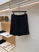 A pair of black Louis Vuitton cotton jersey shorts with an elastic waistband and raw-edge hems, hanging on a black hanger in a luxury boutique.