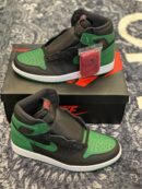 Two Pine Green and black Air Jordan 1 sneakers displayed on a black Nike box.