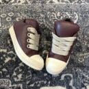 A top-down view of Rick Owens Jumbo Lace sneakers with oversized laces on a patterned rug.