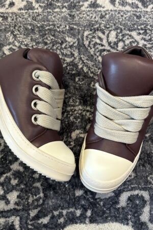 A top-down view of Rick Owens Jumbo Lace sneakers with oversized laces on a patterned rug.