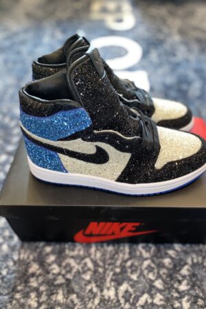 A side profile view of a black, white, and blue glitter-covered high-top sneaker on a Nike box.