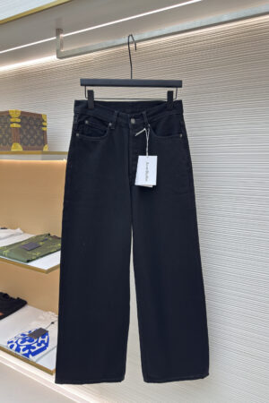 A pair of Acne Studios 1991 Toj loose-fit jeans in a clean black wash hanging in a luxury retail setting.
