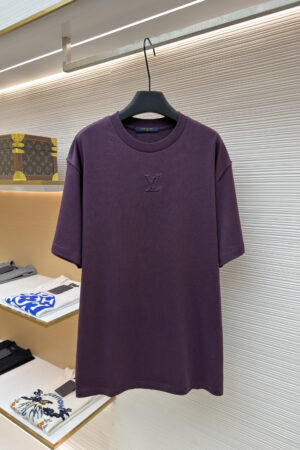 A premium men's deep purple cotton t-shirt featuring a tonal "LV" logo embroidered on the center chest hanging on a display rack.