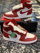 A hand holding a high-top red and white leather sneaker with a textured red swoosh and a white midsole.