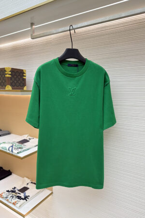 A premium men's emerald green cotton t-shirt featuring a tonal "LV" logo embroidered on the center chest hanging on a display rack.