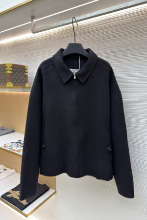 A close-up of a black Acne Studios wool zip-up jacket featuring a sharp collar and silver zipper detail.