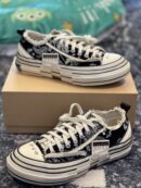 Side view of black and white paisley xVessel low-top sneakers with frayed edges and a layered white midsole on a brown box.