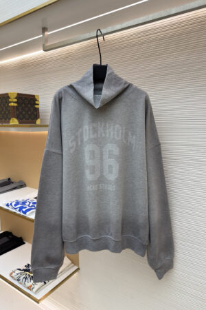 A heather grey Acne Studios oversized hoodie with a white Stockholm 96 chest graphic hanging in a boutique.