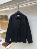 A black Saint Laurent long-sleeved canvas overshirt with a tonal YSL logo on the chest pocket, hanging on a black hanger in a luxury clothing store setting.