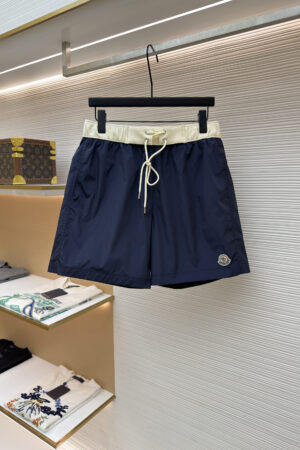 Men's navy blue performance shorts with a contrasting cream waistband hanging on a retail display rack.