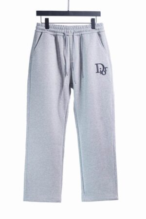 Light grey men's fleece sweatpants hanging on a black hanger, featuring an elastic drawstring waistband, side pockets, and a black embroidered "Dior" logo on the left thigh.