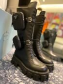 Tall black Prada Monolith combat boots with chunky soles and detachable nylon pouches strapped to the sides.