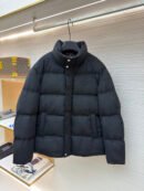 Black wool-textured puffer jacket with a tonal embroidered crest on the chest hanging on a retail display rack.
